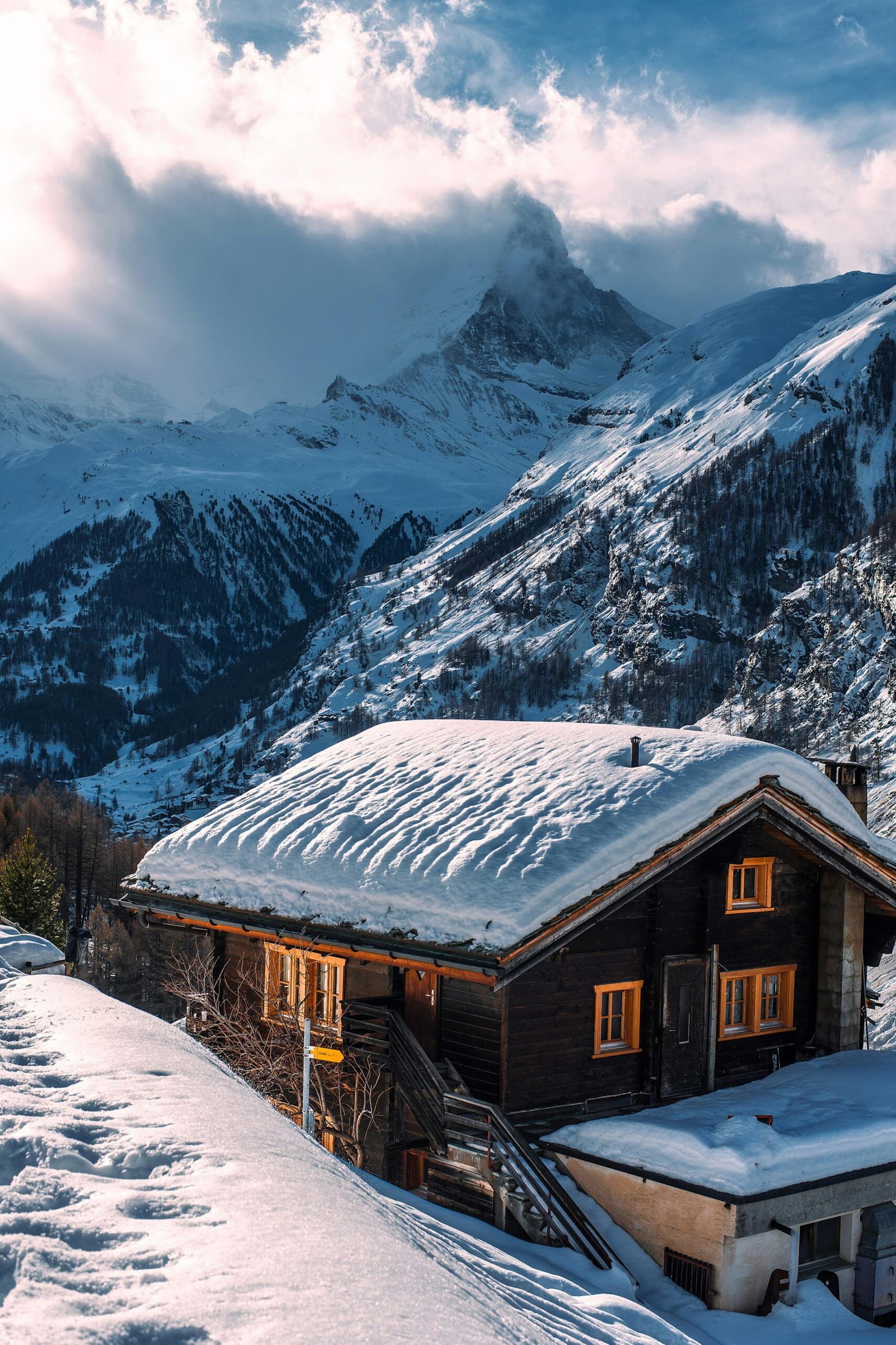 Charming snow-covered chalet set in a serene alpine mountain winter scene.